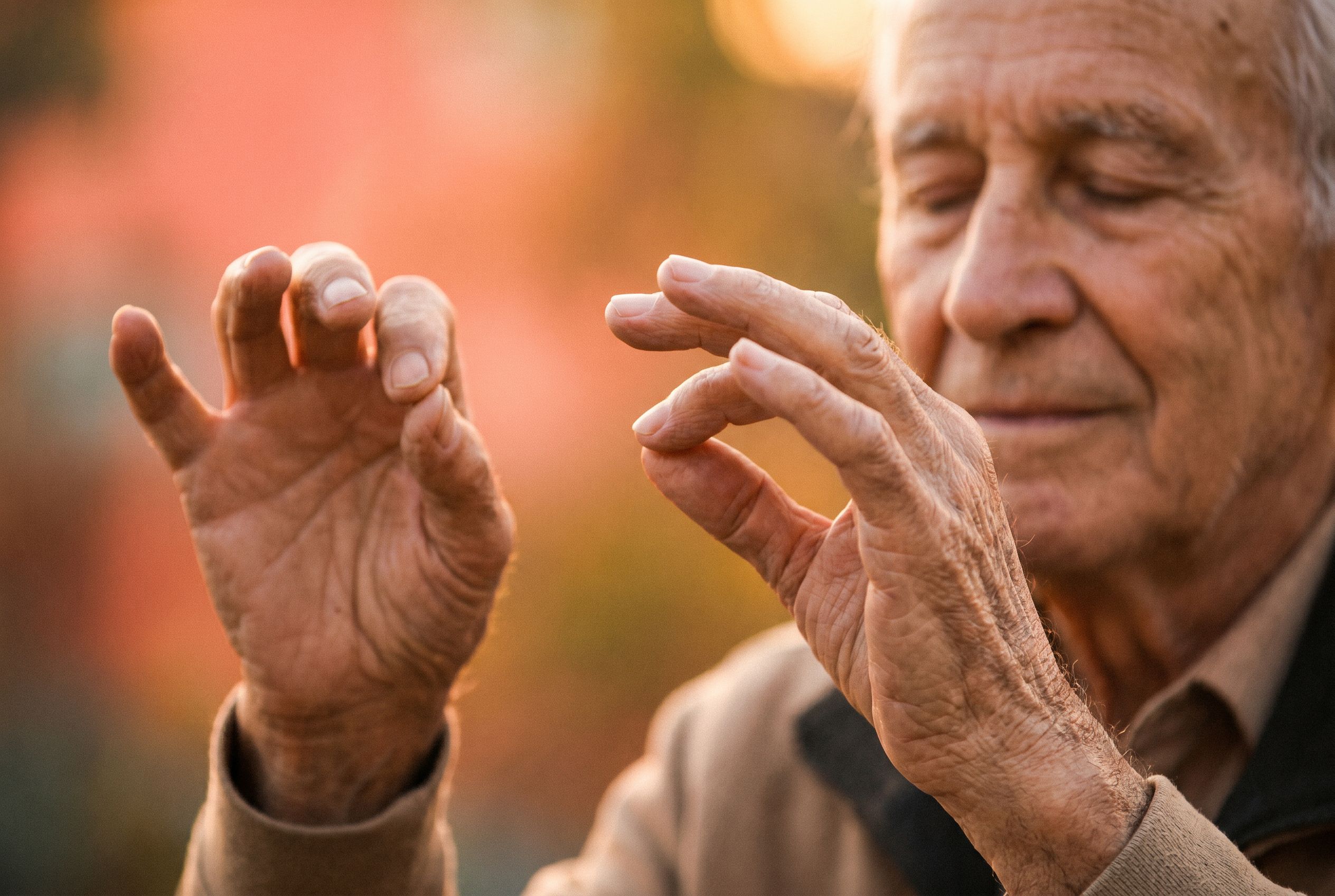 Un homme âgé, les mains levées, danse dans ses pensées en écoutant la musique